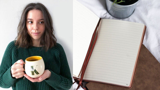 Woman holding a mug beside an open lined notebook resting on a brown cover